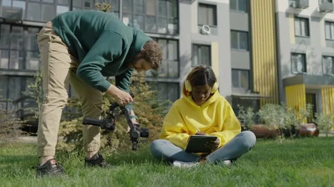 Professional videographer with camera in his hands shoots dark-skinned girl Video stock 244268409