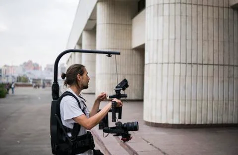 Professional videographer holding camera on 3-axis gimbal which mounted on easy Stock Photos