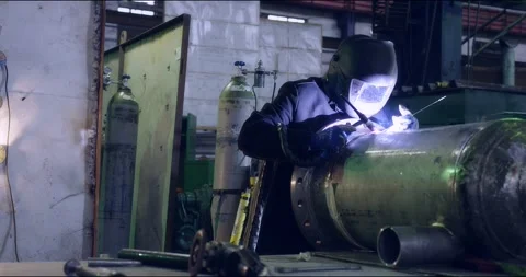 A professional welder makes steel structures at the factory. Stock Footage 166028114