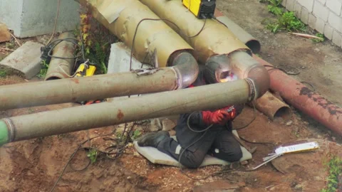 Professional welder performing arc welding on large industrial heating main pipe Stock Footage 344864135