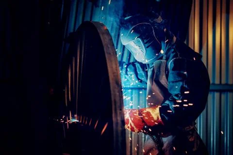 Professional welder performs welding work on metal in protective mask Stock Photos