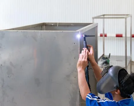Professional welder using a TIG welding torch on a stainless steel metal bo.. 库存照片
