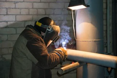 A professional welder welds a pipe with a diameter of DN100 for a process pip Stock Photos