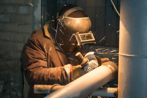 A professional welder welds a pipe with a diameter of DN100 for a process pip Stock Photos