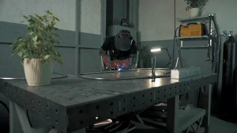 Professional welder works with a welding machine in a shop behind 스톡 동영상 179701719