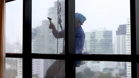 Professional Window Cleaner Using Squeegee on High Rise Building in Bangkok Stock Footage 328079832