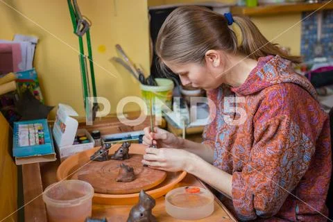 Professional woman potter painting ceramic souvenir penny whistle in pottery Stock Photos