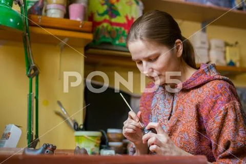 Professional woman potter painting ceramic souvenir penny whistle in pottery Stock Photos