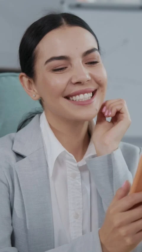 A Professional Woman Smiling While Engaged with Her Smartphone in a Bright Stock Footage 314358490