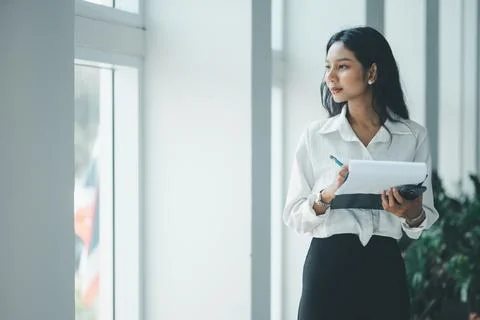 Professional woman writing notes while holding a phone and notepad beside a.. Stock Photos