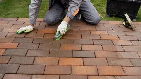 Professional worker applying protective coating to new brick pavers outdoors Fotos Stock