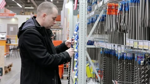 Professional worker browsing hardware store shelf, comparing various drill bit Stock Footage 328020844