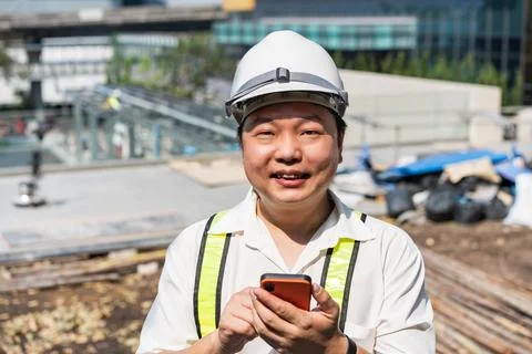 Professional worker checks mobile application near a construction project w.. Stockfoto's