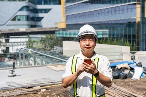 Professional worker checks mobile application near a construction project w.. 스톡 사진