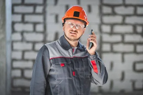 A professional worker at a construction site using a smartphone is always in Stock Photos
