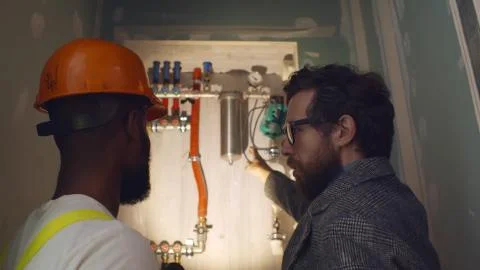 Professional worker explaining owner work of independent heating system in Stock Photos