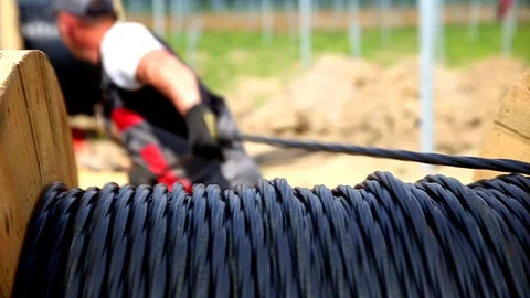 Professional worker installing solar electric cable from big hank. Innovative Stock Footage 105176315
