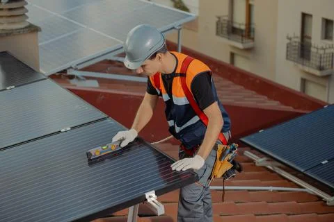 Professional worker installing solar panels on the roof of a house Stock Photos