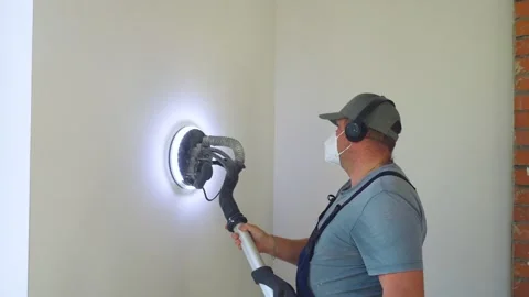 Professional worker in overalls and protective mask sands wall with specialized Stock Footage 319210675