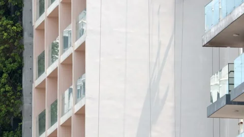 A professional worker paints the tall exterior wall of a building Stock Footage 342807582