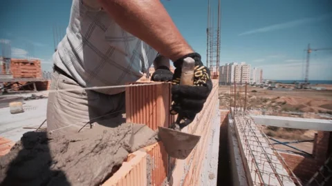 Professional worker rapidly gets red brick and place it on building wall Stock Footage 143217123