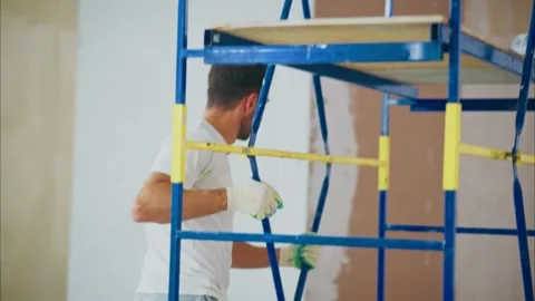 A Professional Worker on a Scaffold Prepares to Paint a Wall, Demonstrating 스톡 동영상 316061411