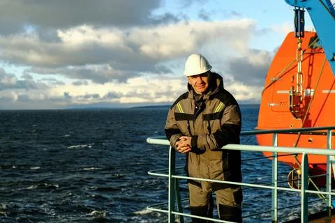 A Professional Worker on a Ship Deck, Overlooking the Vast Ocean Horizon in the Stock Photos