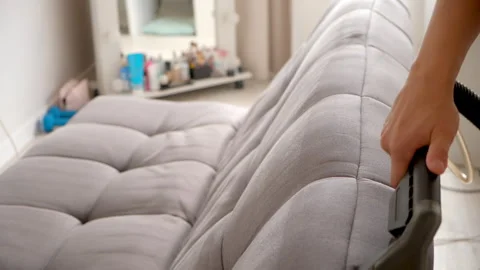 Professional worker utilizes vacuum cleaner to clean sofa, banishing dirt dust. Stock Footage 311801196