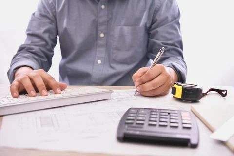 A professional working on project plans with calculator, keyboard and measu.. Foto stock