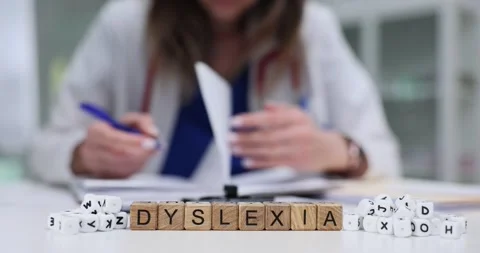 Professional writes patient notes near blocks spelling Dyslexia Stock Footage 310219041