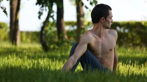 Professional yoga man practicing in park. Bare-chested guy doing yoga poses Stock Footage 77336897