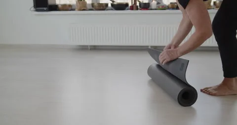 Professional yoga trainer rolls out a mat on the floor preparing for training Stock Footage 156765320