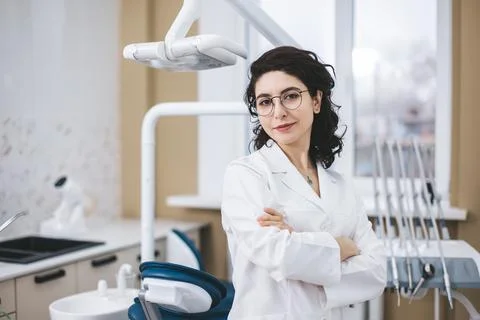 Professional young dentist posing beside modern equipment in a dental clinic. Stock Photos