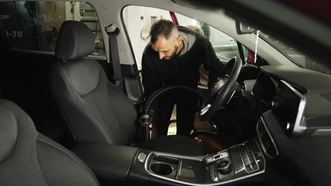 Professional young male worker using vacuum cleaner for dirty car interior. Stock Footage 233983357