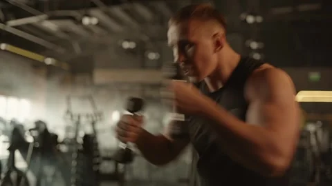 Professional young muscular man is practicing shadow boxing with dumbbells Stock Footage 269130163