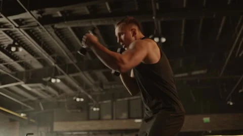 Professional young muscular man is practicing shadow boxing with dumbbells Stock Footage 269130231