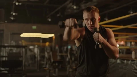 Professional young muscular man is practicing shadow boxing with dumbbells Stock Footage 269130297