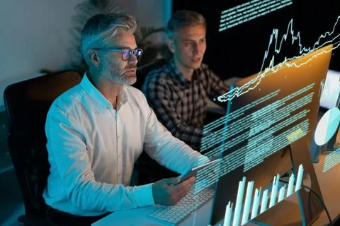 Professionals Analyzing Data and Graphs on Computer Screens in Office Stock Photos