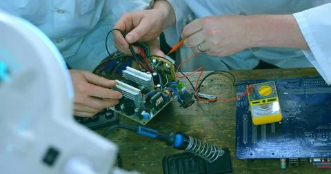 Professionals collaborate on electronic hardware, possibly for repair or Stock Photos