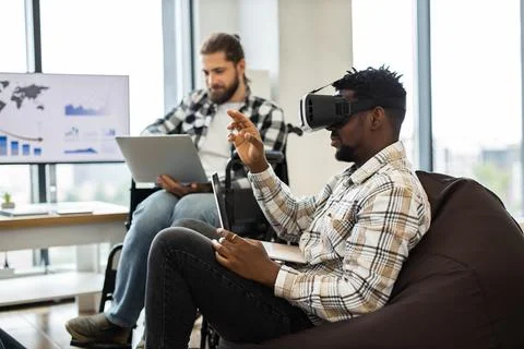 Professionals collaborating with virtual reality and laptops in office space Stock Photos