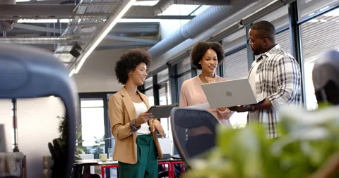 Professionals discussing work while holding laptop and tablet in office Stock Footage 298134771