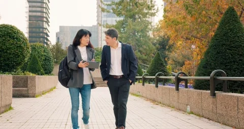 Professionals engage in discussion while strolling in the financial district 库存影片 297708658