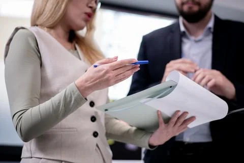 Professionals reviewing documents during a workplace discussion while exchanging 写真素材