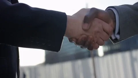 Professionals in suits shaking hands in the sunlight, in slow motion Видео 83629149