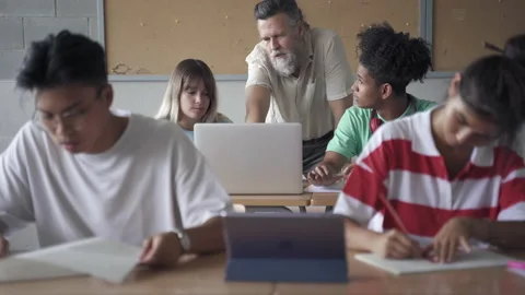 Professor assisting multi-ethnic students in modern Secondary School classroom Stock Footage