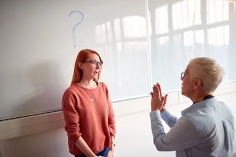 Professor explaining and questioning student in classroom on board. Stock Photos