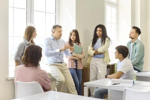 Professor explaining to diverse students during group discussion in classroom 스톡 사진