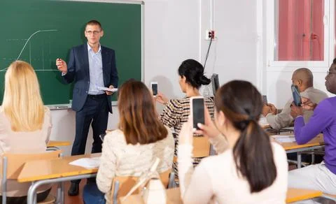 Professor explaining function graph to adult students in auditorium 库存照片