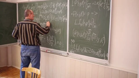 Professor inserting data in integral equations on blackboard in classroom. Video stock 69988668