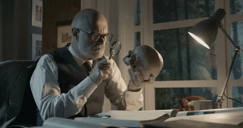 Professor sitting at desk and checking a human skull Stock Footage 151181123